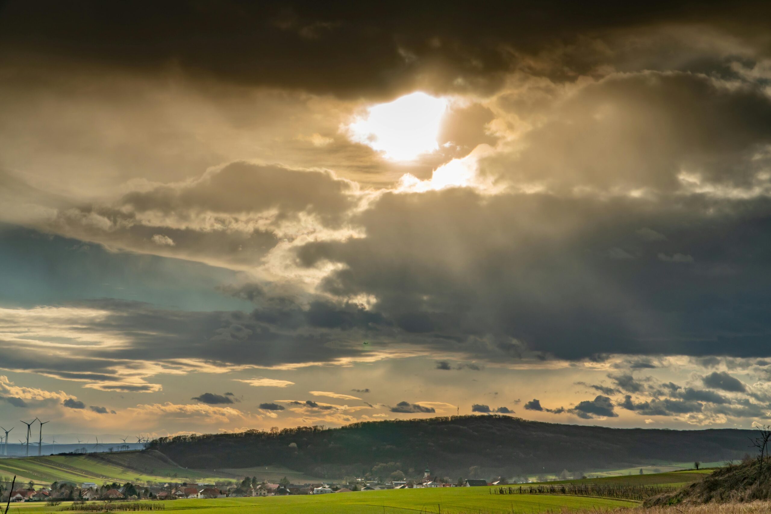 Golden sunset over Austrian fields with dramatic clouds and sun rays breaking through.